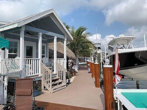 A marina with a covered dock area, a boat, and a building with a porch. - Tiny home in Key Largo with Private Dock, Tiki Hut and Boat Lift (Key Largo)