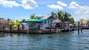 A waterfront property with a dock, a thatched-roof structure, and a building with a sloped roof. - Tiny home in Key Largo with Private Dock, Tiki Hut and Boat Lift (Key Largo)