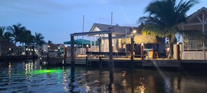 A waterfront property with a dock, a covered seating area, and a house with a thatched roof. - Tiny home in Key Largo with Private Dock, Tiki Hut and Boat Lift (Key Largo)