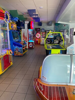 An indoor arcade with various gaming machines, including a pirate-themed game and a toy chest game.