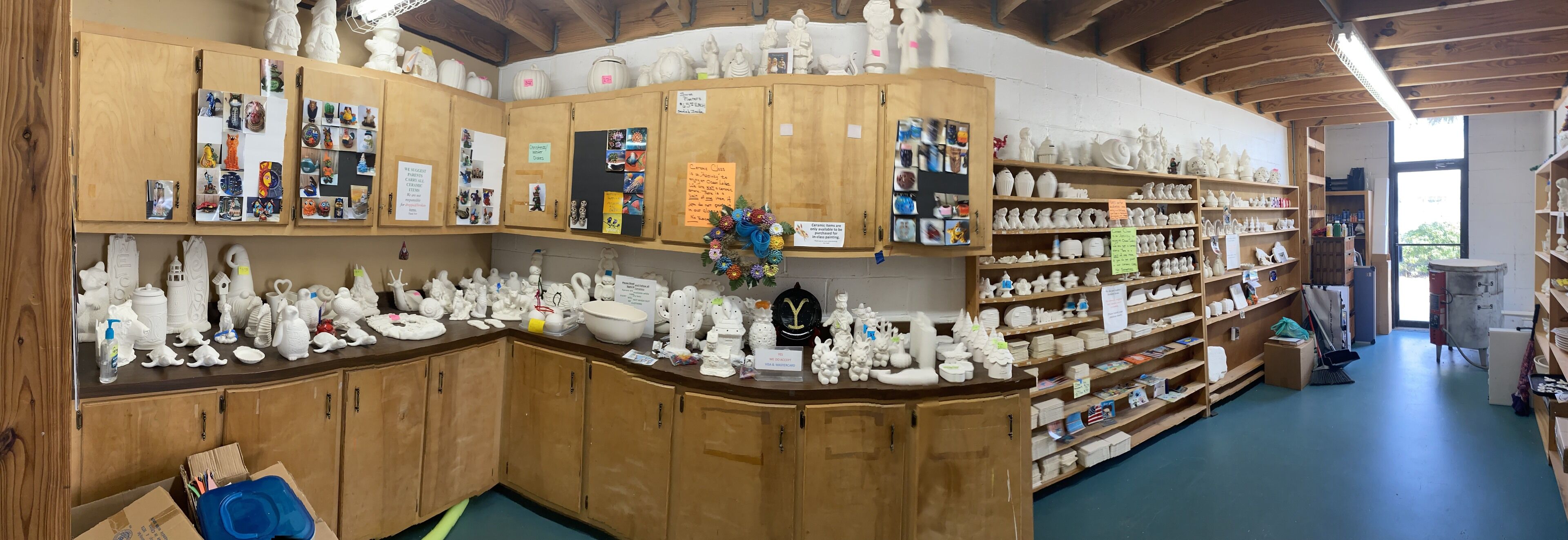 A pottery studio with wooden cabinets and shelves filled with ceramic items.