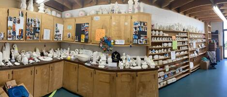 A pottery studio with wooden cabinets and shelves filled with ceramic items.