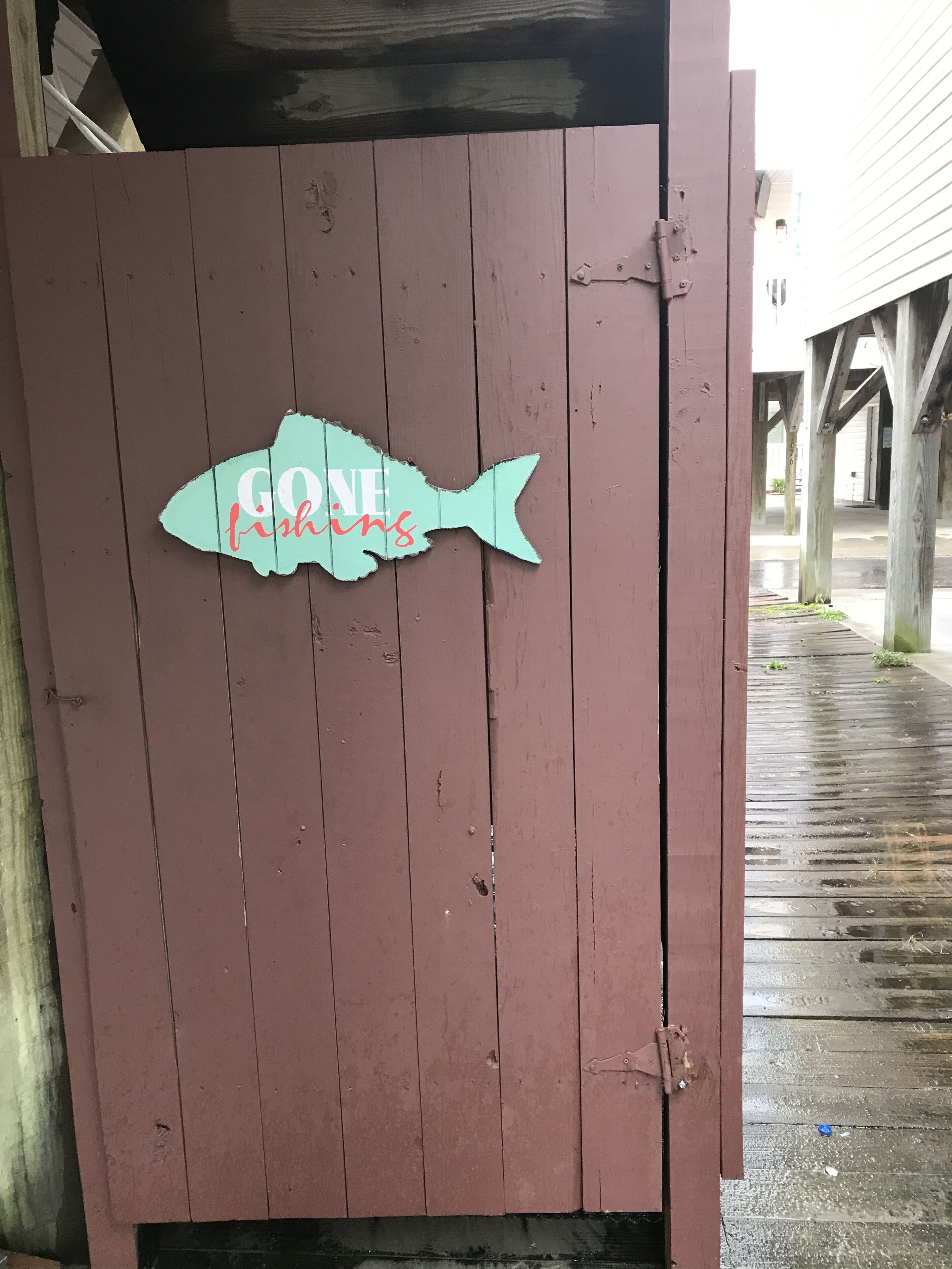 A wooden door with a fish-shaped sign that reads "GO FISHING."