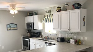 A kitchen with white cabinets, a large island with stools, a ceiling fan, and a sign that reads "Welcome". - Book now for the SUMMER before it’s gone @ Ocean Lakes Family Campground!! (Myrtle Beach)