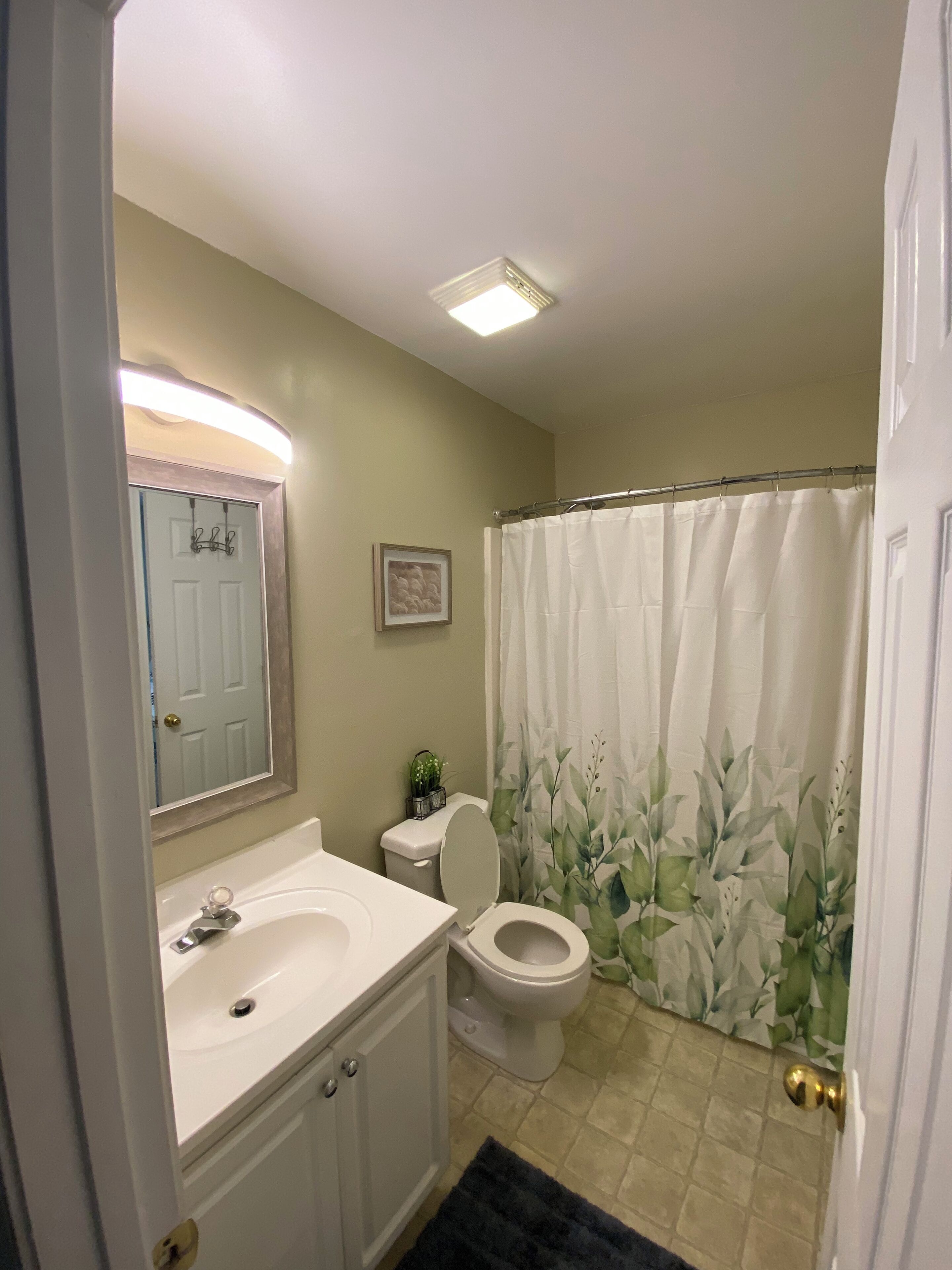 A bathroom with a white sink, toilet, and shower curtain.