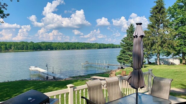 A deck with outdoor furniture overlooking a lake, a grill, and a dock with a boat. - The Musky Cabin on the Big Eau Pleine Reservoir! (Auburndale)
