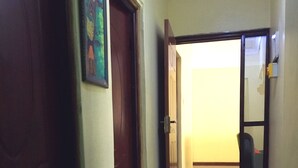 Un couloir avec une porte en bois, une porte dotée d’un panneau de verre et un sol carrelé.