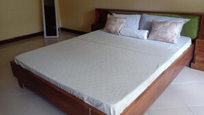 Un grand lit avec un cadre en bois et une tête de lit recouverte d’un tissu vert.