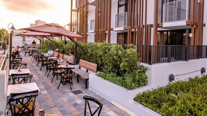 An outdoor patio area with tables and chairs, a wooden fence, and a building with balconies. - UPSUN HOTEL (Miami Beach)