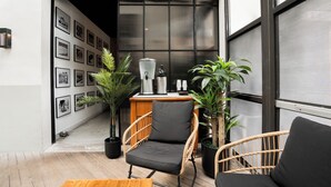 A modern interior with a seating area, a coffee station, and a wall adorned with framed pictures. - UPSUN HOTEL (Miami Beach)
