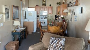 Un salon chaleureux avec un canapé, une table à manger et une cuisine en arrière-plan.