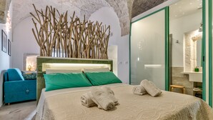 A modern bedroom with a large bed, green pillows, and a unique wooden branch decoration. - Sunsets over Ostuni and the sea - OSTUNI STYLE (Ostuni)
