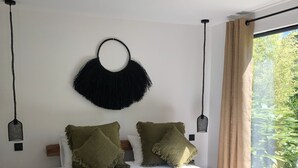 Une chambre à coucher avec un lit en bois, une literie blanche et des coussins décoratifs verts.