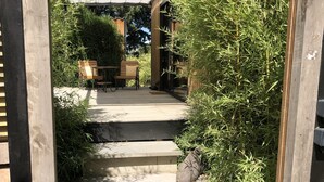 Une terrasse en bois avec des marches en pierre menant à un espace salon abrité.