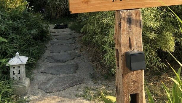 Un panneau en bois portant l’inscription « Lodge Kembali Privé », placé dans un cadre naturel, avec un chemin de pierres qui traverse la végétation.