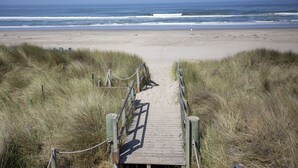 En träpromenad som leder till en strand med utsikt över havet.