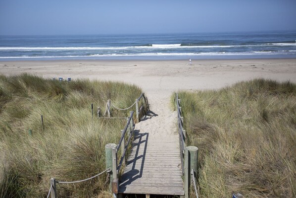 A wooden boardwalk leading to a beach with ocean views.