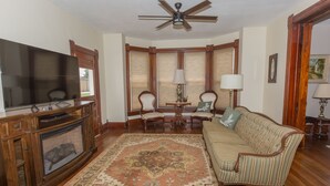 A living room with a fireplace, television, and a ceiling fan.