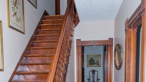A wooden staircase with a handrail, a rug on the floor, and a chair in the background.