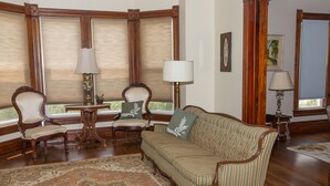 A room with a striped sofa, two armchairs, a small table, and a patterned rug.