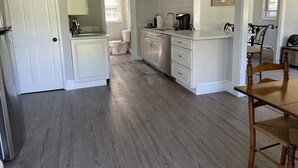 Een moderne keuken met witte kasten, een roestvrijstalen koelkast en een eethoek met een houten tafel en stoelen.