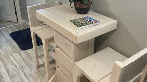 Een eetgedeelte met een houten tafel en stoelen, een potplant en een schilderij aan de muur.