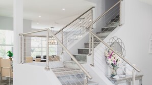 A modern staircase with metal railings and a marble finish, leading to a second floor. - Great reviews,Brand new,waterfront,heated pool, hot tub & beach access -14 pple  (Bonita Springs)