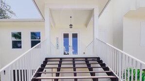 A staircase leading to a door with a "WELCOME" sign, a view of the sky, and a building with windows. - Great reviews,Brand new,waterfront,heated pool, hot tub & beach access -14 pple  (Bonita Springs)