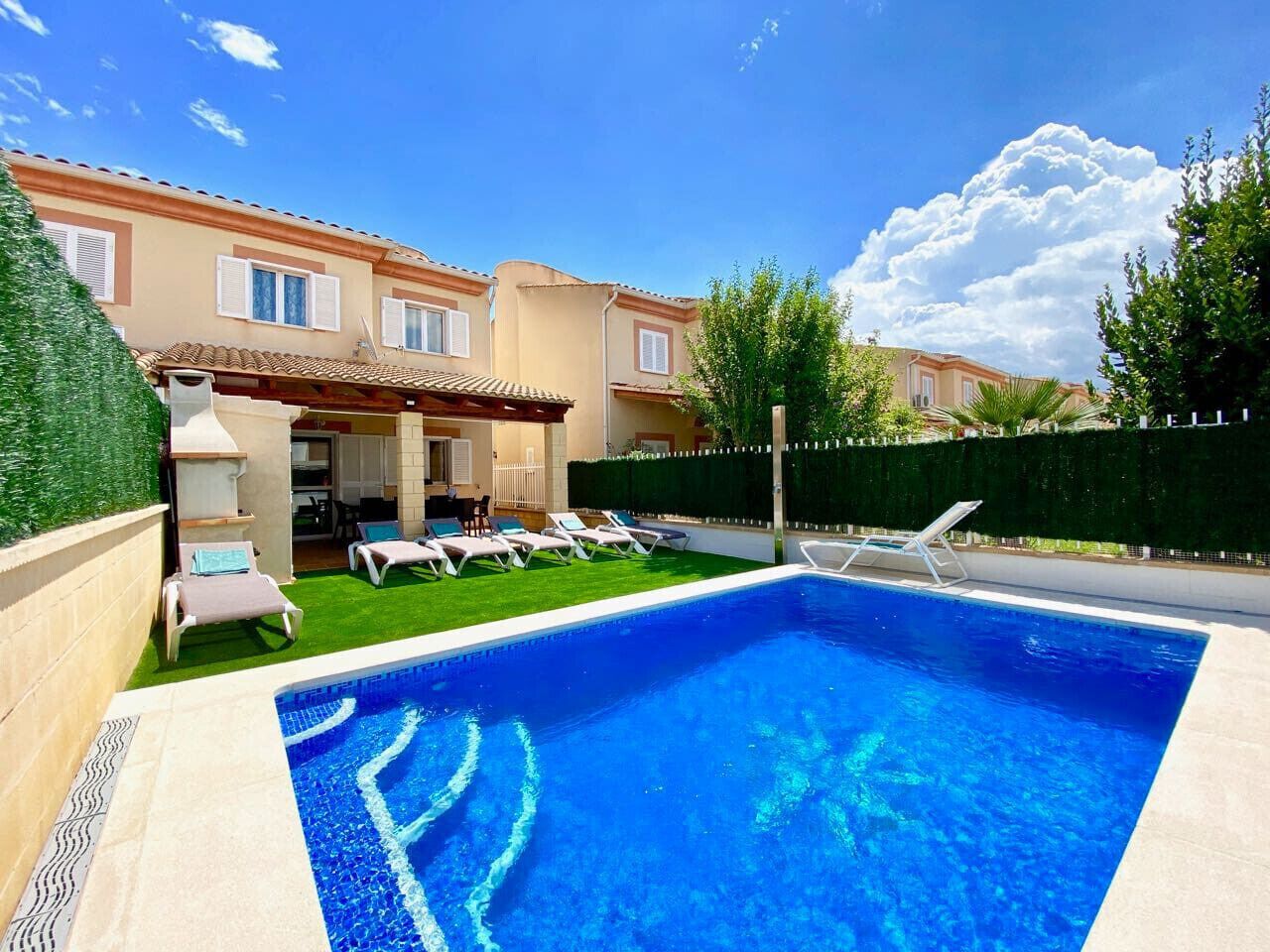 Una piscina amb gandules, un porxo cobert i un edifici amb teulada enrajolada.