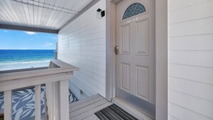 Une maison située sur la côte, avec une façade blanche, une porte portant l’inscription « Mare » et une vue sur l’océan.