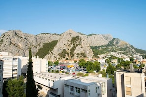 A cityscape with a mountainous backdrop, featuring a parking lot and buildings with flat roofs. - New Modern Apartment With View in Omis, Croatia (Omis)
