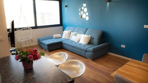 A modern living room with a sectional sofa, a hanging chair, a dining table with two chairs, and a decorative wall with circular mirrors. - New Modern Apartment With View in Omis, Croatia (Omis)
