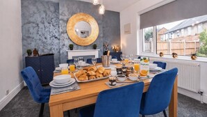 Un comedor con una mesa de madera dispuesta para el desayuno, un espejo grande y vistas al exterior.