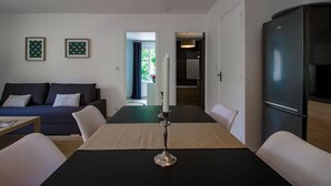 Una sala moderna con un sofá oscuro, una mesa de comedor con un centro de velas y un refrigerador negro.