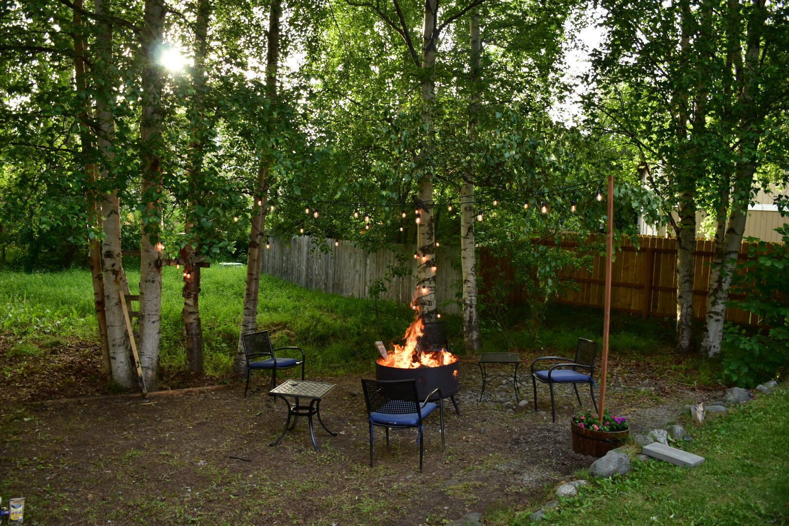 An outdoor patio area with a fire pit, two metal chairs, and a table.
