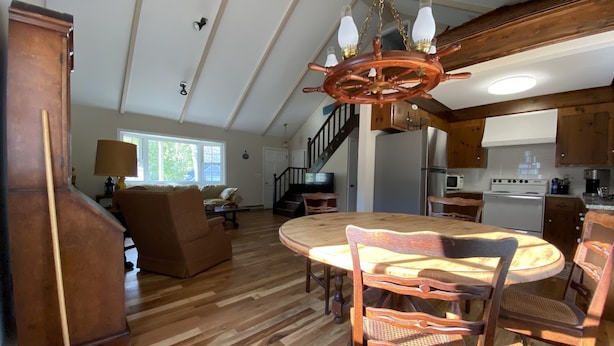 A spacious living area with a wooden dining table, chairs, and a chandelier. A staircase leads to an upper level. - Harwich home close to the beach (Harwich)