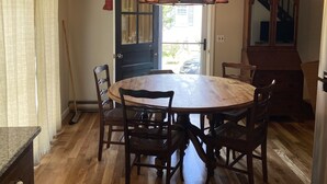 A dining area with a wooden table and chairs, a chandelier, and a large mirror. - Harwich home close to the beach (Harwich)