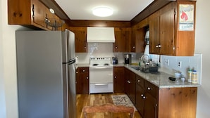 A kitchen with wooden cabinets, a stainless steel refrigerator, a stove, and a wooden bench. - Harwich home close to the beach (Harwich)