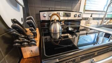 A kitchen with a stainless steel stove, a kettle, and a knife block.