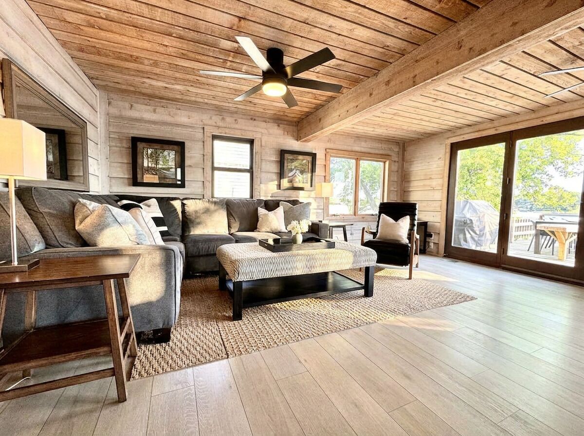 Un salon spacieux doté d’un plafond en bois, d’un ventilateur de plafond, d’un ensemble de canapés, d’une table basse et de grandes fenêtres.
