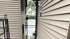 A narrow concrete staircase leading to a door, flanked by beige siding walls and a brick base.