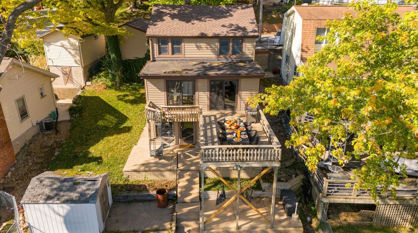 A two-story house with a deck, a small porch, and a fenced backyard.