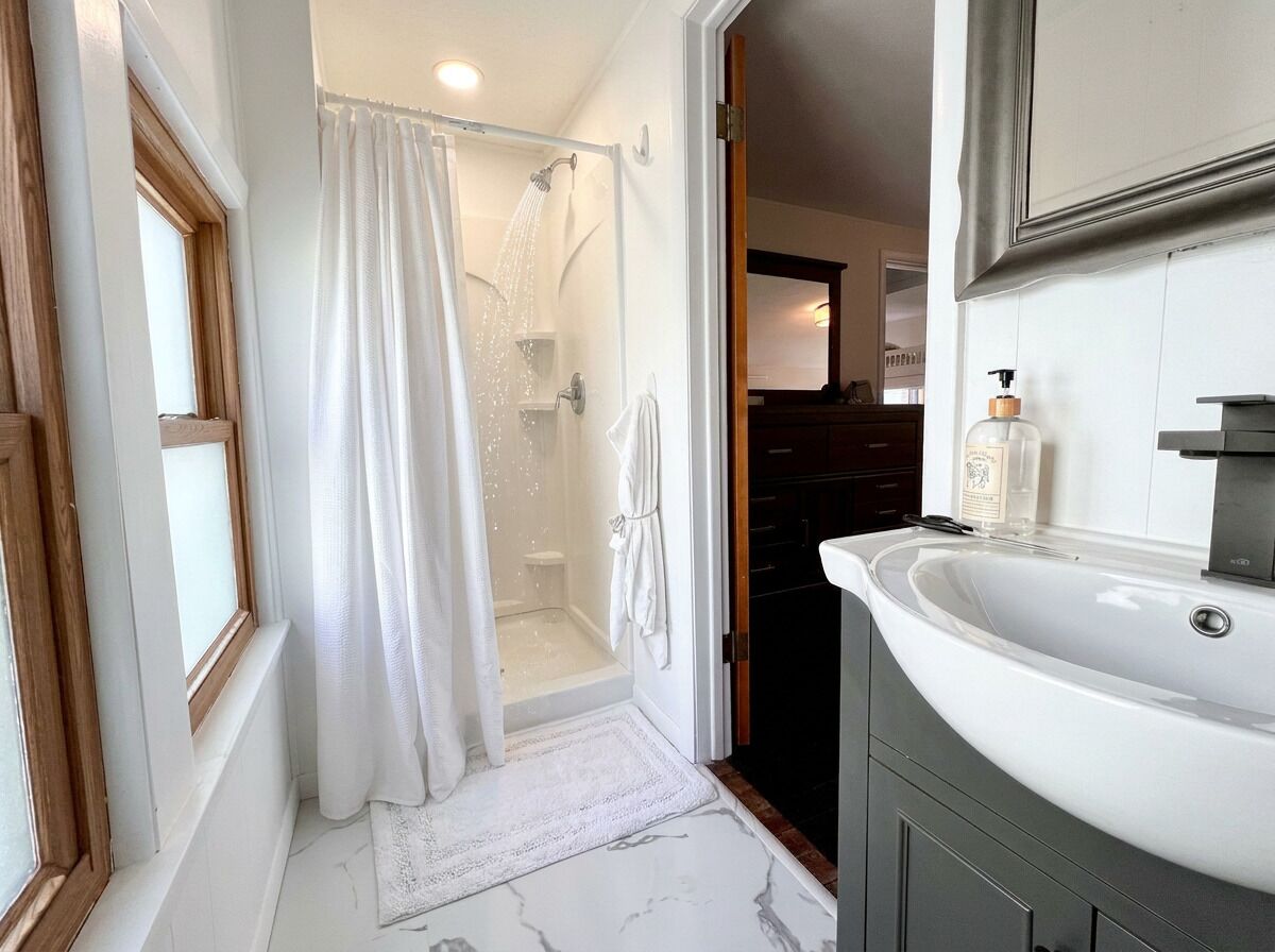 A bathroom with a shower, a sink, and a mirror.