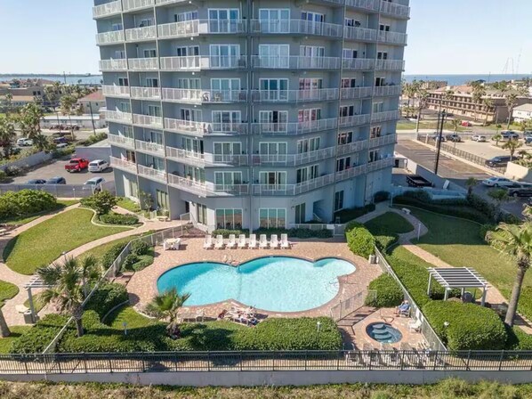 A multi-story hotel with a swimming pool, outdoor seating, and a view of the sea. - WOW!!!!, ON BEACH, 7TH FL, AMAZING BAY and FIREWORKS VIEW! SPI License 20232542 (South Padre Island)