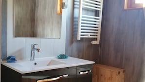 Un baño con tocador de madera, espejo, lavamanos blanco y un perchero para toallas.