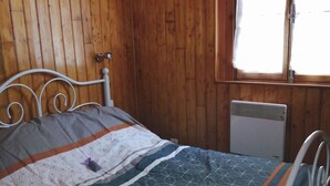 Una habitación con paneles de madera, una cama, una ventana y un radiador.