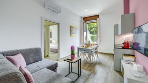 Una sala moderna con un sofá gris, una mesita y una zona de cocina con una mesa de comedor y sillas.