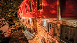 A red building with a stone facade, a small outdoor seating area, and a visible window. - PetraAda Bozcaada (Bozcaada)