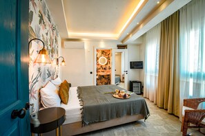 A bedroom with a bed, bedside table, lamp, and a view of a bathroom. - PetraAda Bozcaada (Bozcaada)