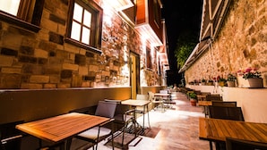 An outdoor cafe with tables and chairs, stone walls, and potted plants. - PetraAda Bozcaada (Bozcaada)